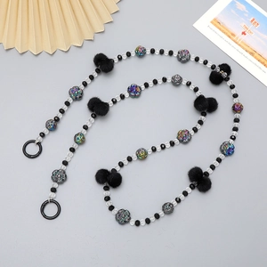 Detail of DIY beaded strap with colorful floral charms and black plush pom poms