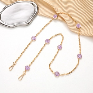 Detail of gold chain with purple smiley faces and lobster clasps on elegant tray