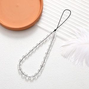 Close-up of transparent cube beads on a black cord phone charm against soft background