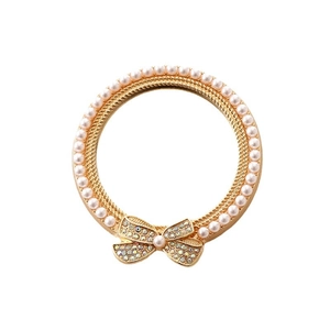 Elegant gold-tone circular frame with white pearls and a colorful rhinestone bowknot