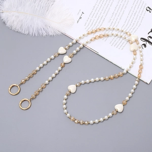 Chaîne élégante en perles avec cristaux ambrés et breloques cœurs sur fond de magazine
