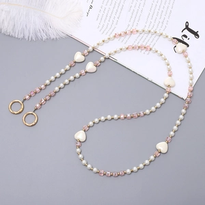 Chaîne de perles chic avec cristaux roses et breloques cœur blanc sur fond gris élégant