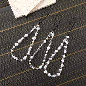 Three creative irregular pearl phone straps with gold and silver beads on a wooden desk