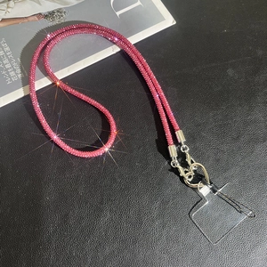 Detailed view of pink rhinestone phone strap with silver metal clasp on black leather