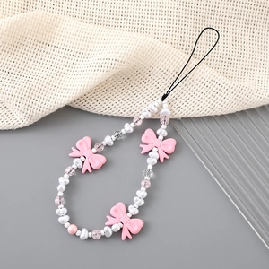 Handmade beaded phone charm with pink bows and heart beads on a soft aesthetic background