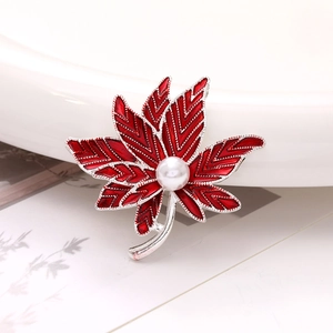 Macro detail of red maple leaf brooch with silver veins and a centered white pearl