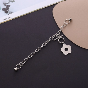 Silver link chain charm with flower pendant and magnetic OT clasp on textured surface