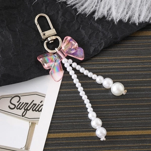 Porte-clés avec nœud rose iridescent et perles acryliques sur fond de bois sombre