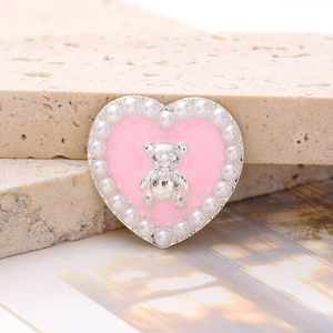 Close-up of heart-shaped shoe charm featuring pink enamel, silver bear and pearls