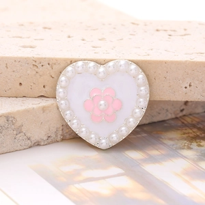 Detail view of heart-shaped shoe charm with white pearls and pink flower center