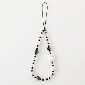 Elegant beaded mobile phone strap with white faux pearls and black beads on beige background