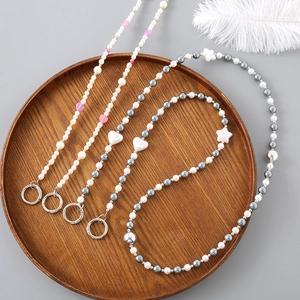 Chaîne bandoulière en perles et cœurs avec boucles métalliques sur plateau en bois