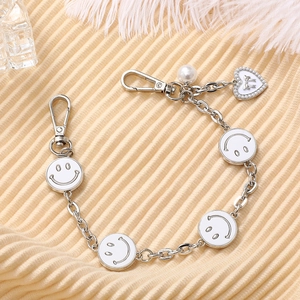 Silver metal chain phone strap with smile face charms and heart pendant detail