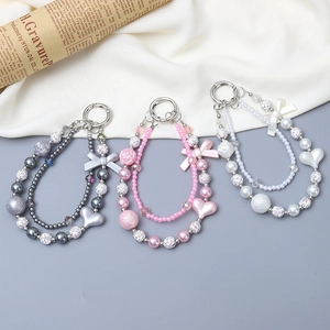 Three beaded phone straps with heart, pearl, and bow charms in grey, pink, and white tones