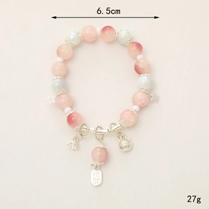 Pink and blue crystal beaded bracelet with lucky cat and bell charms on plain background