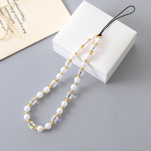 Elegant pearl and crystal beaded phone charm strap with gold accents on a white jewelry box