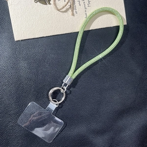 Detail of glittery lime green mesh phone strap with silver spring ring on black leather background