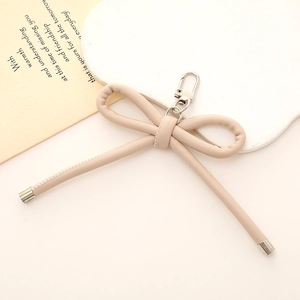 Dettaglio portachiavi a fiocco in pelle PU beige con moschettone in metallo argento elegante