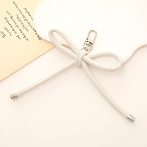Dettaglio del fiocco in pelle PU bianca con moschettone d'argento su sfondo minimalista