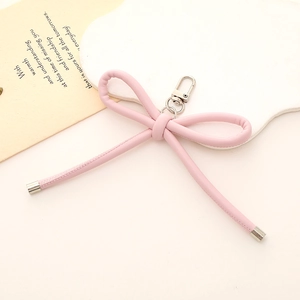 Dettaglio di un ciondolo a fiocco in pelle PU rosa con moschettone argentato e punte in metallo
