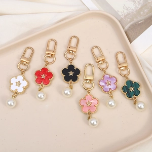 Colorful floral enamel keychains with star center and pearl charms in various vibrant shades