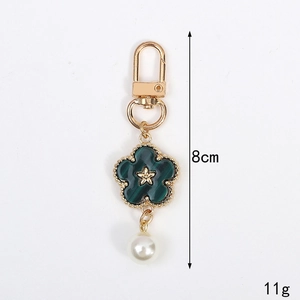 Floral keychain with green enamel flower, gold star accent, and white pearl drop charm