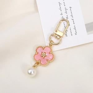 Detail of pink flower keychain with golden lobster clasp and white faux pearl accent