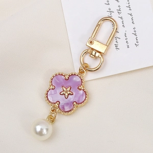 Detailed macro view of a purple flower keychain with a white pearl and golden clasp