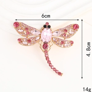 Sparkling dragonfly brooch with pink crystals and dimensions 6cm x 4.8cm shown on beige