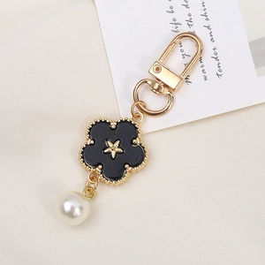Detail of black enamel flower charm keychain with gold star and faux pearl bead