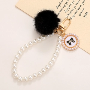 Détail d'un porte-clés perles avec boule en peluche noire et pendentif nœud numéro cinq