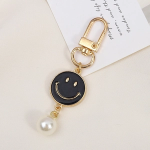 Detail of flower keychain with black enamel smile charm and white pearl drop bead