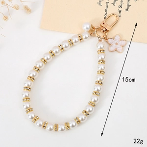 Detail view of a 15cm pearl phone strap with gold accents and pink flower charm
