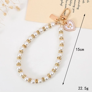 Elegant pearl phone charm with rhinestone heart pendant and gold bow knot detail