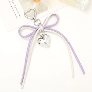 Close-up of purple and beige leather bow charm with silver heart pendant and heart-shaped clasp