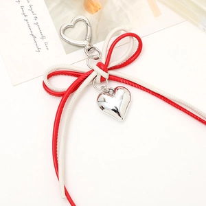 Detail of red and white leather bow charm with silver heart pendant and metal hook