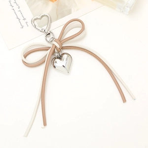 Detail of bicolor leather cord bow charm with silver heart pendant and spring clasp