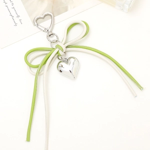 Close-up of heart-shaped silver pendant with green and cream leather bow keyring
