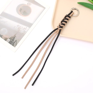 Detail of hand-woven leather tassel keychain with silver metal ring in beige and black