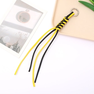 Macro detail of hand-woven black and yellow leather keychain with silver metal ring