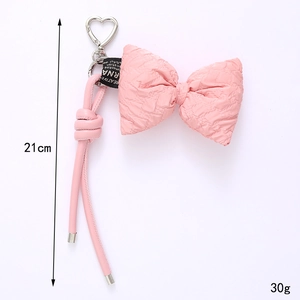 Pink checkered bow keychain with silver heart clasp and faux leather strap on white background