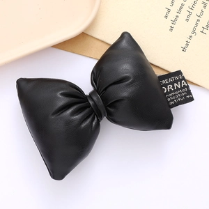 Close-up of black 3D padded faux leather bow with gold-lettered woven label detail