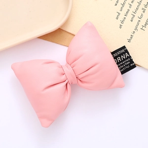 Detail of pink padded leather bow with gold-stamped creative label for DIY fashion accessories