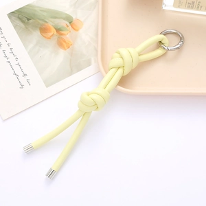 Detail of hand-woven light yellow leather knotted keychain with silver spring clasp