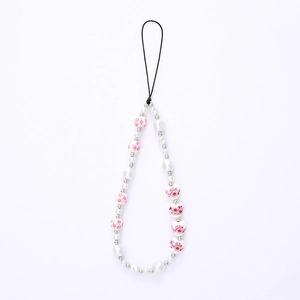 Beaded phone charm with white faux pearls and heart-shaped floral ceramic beads on white backdrop