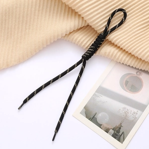 Close-up of black and gold woven cord with roman knot detail and plastic end caps