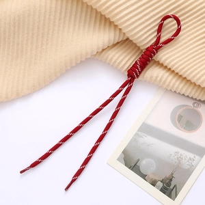Detailed view of red and white woven cord pendant with round ring for bags and phones