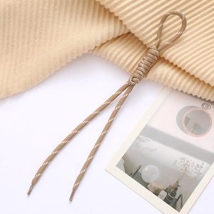 Khaki woven phone strap with white dots and stylish Roman knot detail in a cozy setting
