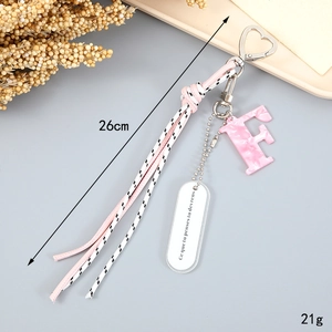Detail of pink marble letter F keychain with woven tassel and heart-shaped metal clasp