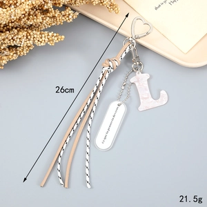 Detail of pink marble letter L pendant with woven tassel and French quote keychain
